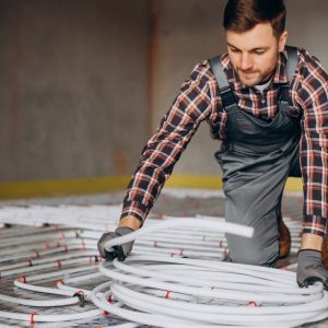 Service man instelling house heating system under the floor